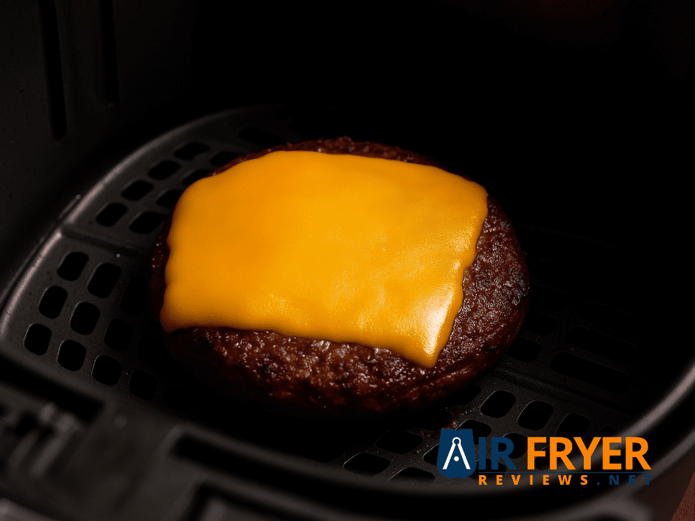 A slice of cheese melting on a burger in the air fryer.