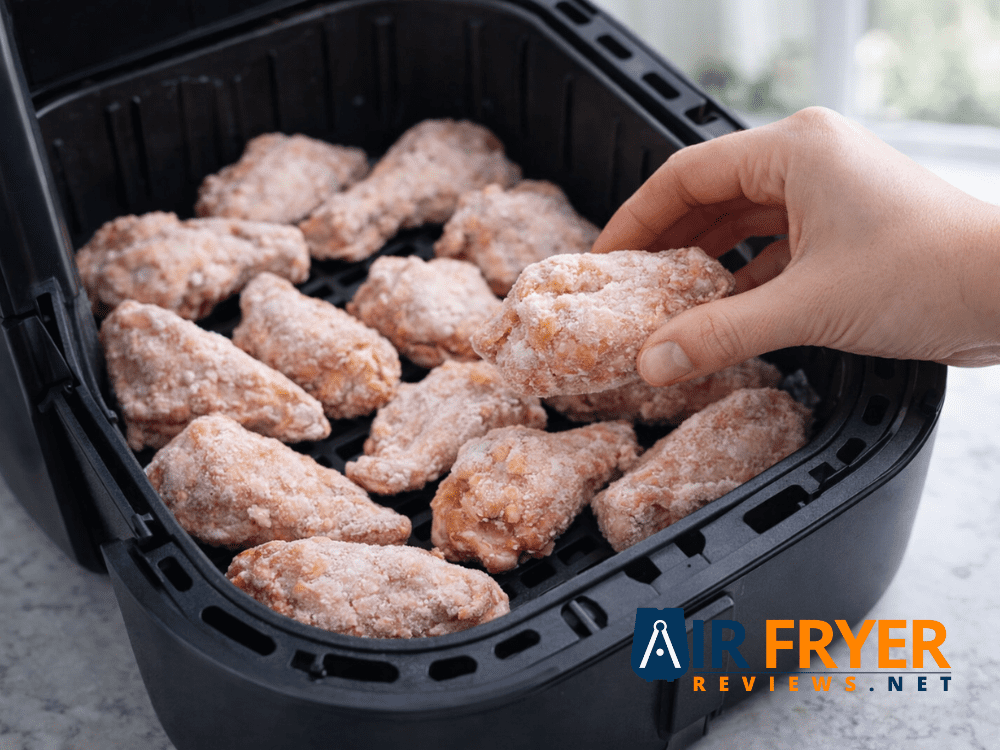Frozen chicken wings straight from the freezer placed in an air fryer basket before cooking Air Fryer Reviews