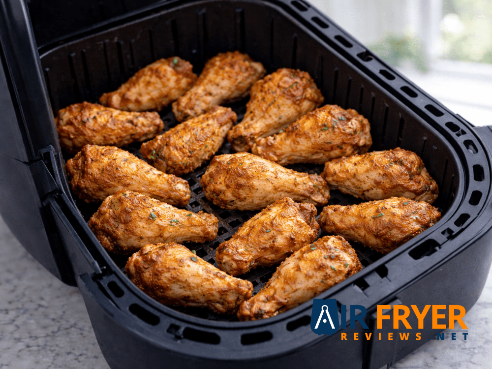 Fully cooked crispy chicken wings inside an air fryer evenly browned and ready to serve Air Fryer Reviews
