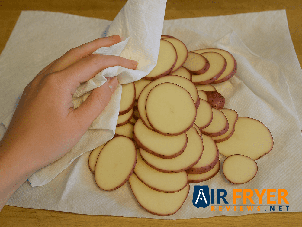 Slim hand patting thin potato slices dry with a paper towel Air Fryer Reviews