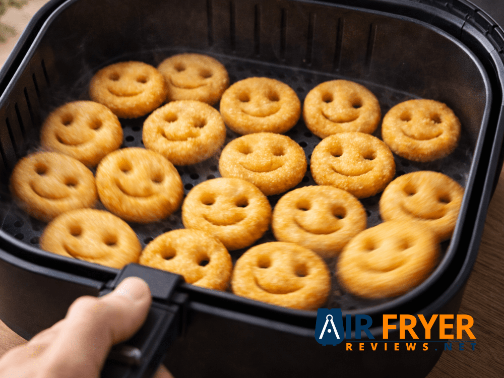 hand shaking air fryer basket with smiley fries to redistribute for even cooking