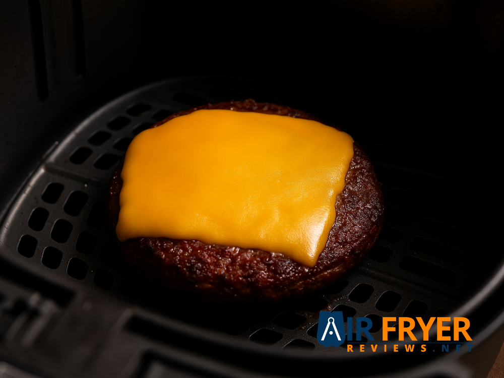 A slice of cheese melting on a burger in the air fryer.