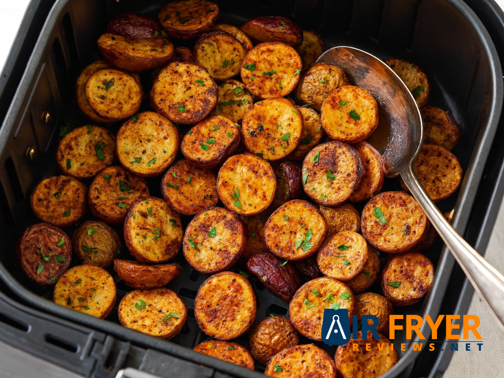 Seasoned potato halves cooked in an air fryer with a spoon inside Air Fryer Reviews